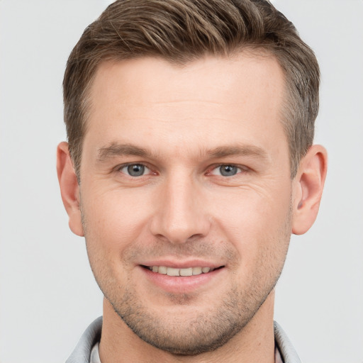 Joyful white young-adult male with short  brown hair and grey eyes