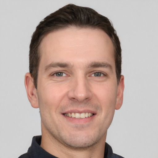 Joyful white young-adult male with short  brown hair and grey eyes