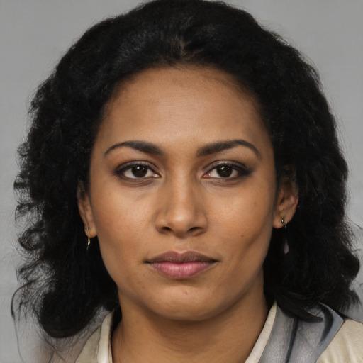 Joyful black young-adult female with long  black hair and brown eyes