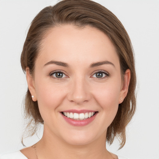 Joyful white young-adult female with medium  brown hair and grey eyes