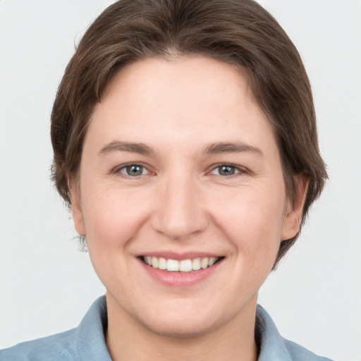 Joyful white young-adult female with short  brown hair and grey eyes