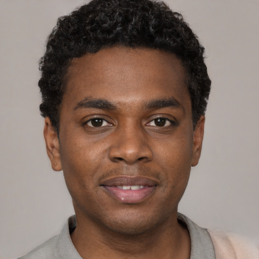 Joyful black young-adult male with short  black hair and brown eyes