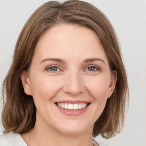 Joyful white young-adult female with medium  brown hair and grey eyes