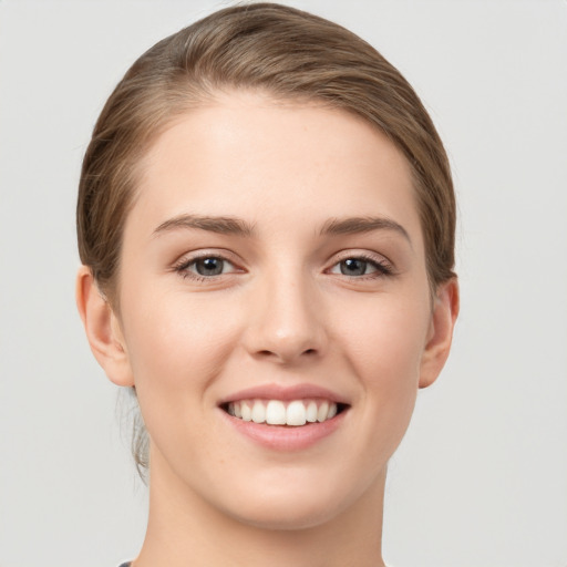 Joyful white young-adult female with medium  brown hair and grey eyes