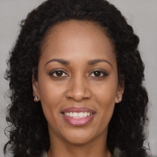 Joyful black young-adult female with long  brown hair and brown eyes