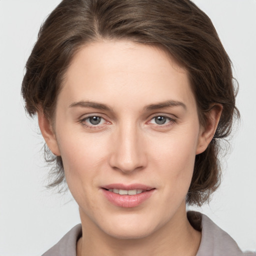 Joyful white young-adult female with medium  brown hair and grey eyes