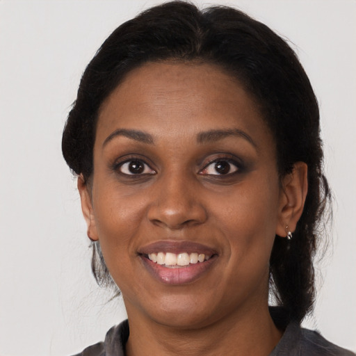 Joyful black young-adult female with long  brown hair and brown eyes