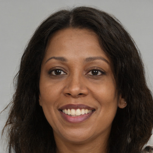 Joyful black adult female with long  brown hair and brown eyes