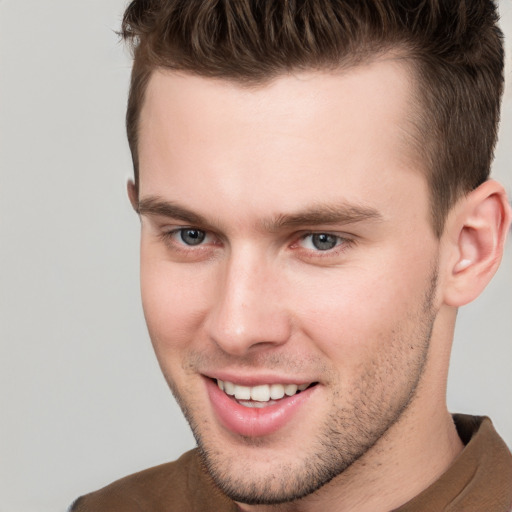 Joyful white young-adult male with short  brown hair and grey eyes