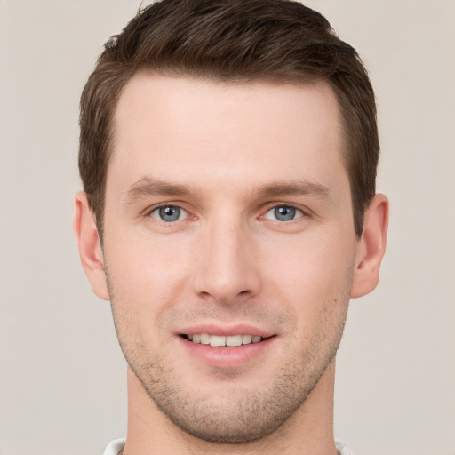 Joyful white young-adult male with short  brown hair and grey eyes