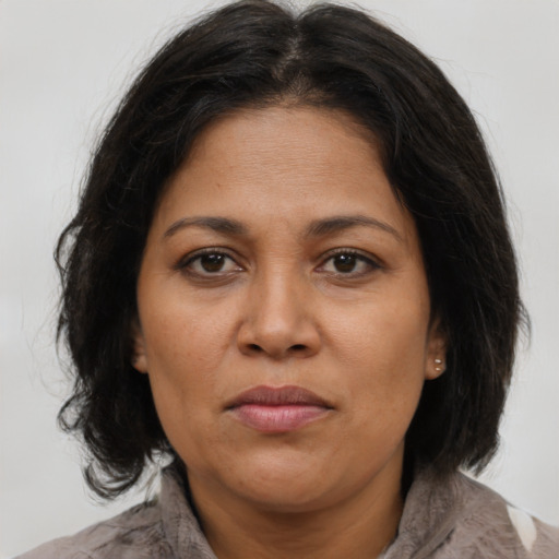 Joyful latino adult female with medium  brown hair and brown eyes