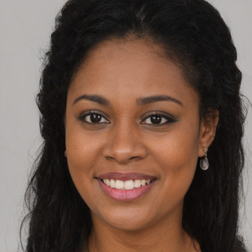Joyful black young-adult female with long  brown hair and brown eyes