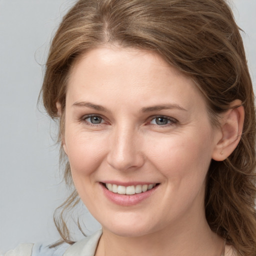 Joyful white young-adult female with medium  brown hair and grey eyes