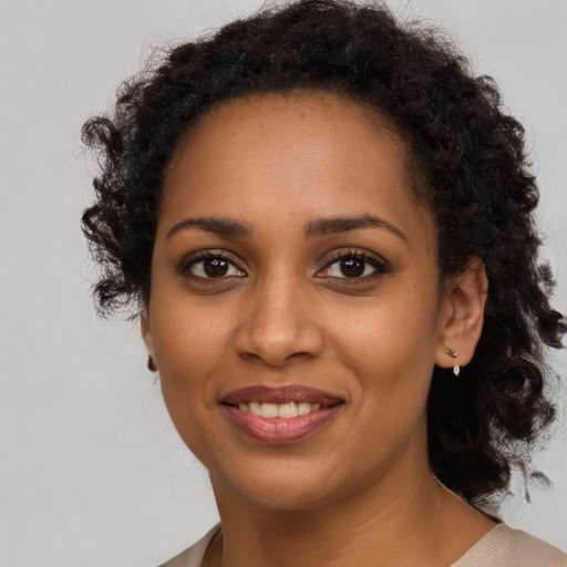 Joyful black young-adult female with long  brown hair and brown eyes