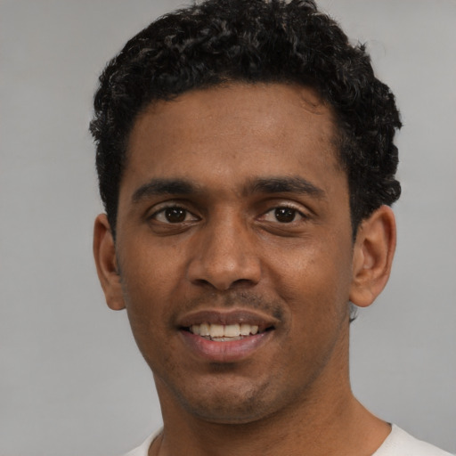 Joyful black young-adult male with short  black hair and brown eyes