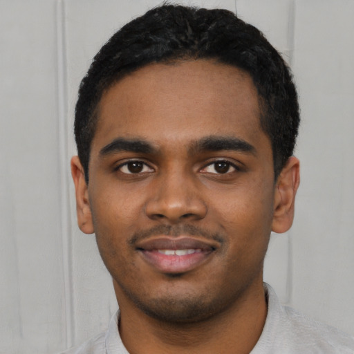 Joyful black young-adult male with short  black hair and brown eyes