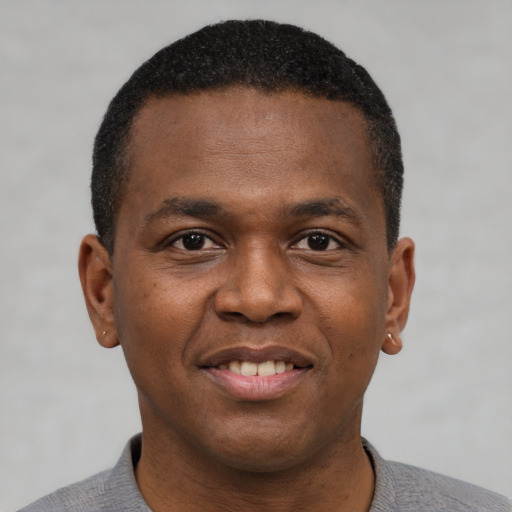 Joyful black young-adult male with short  brown hair and brown eyes