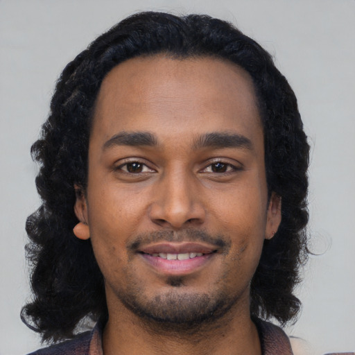 Joyful black young-adult male with medium  black hair and brown eyes