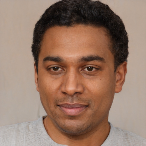 Joyful black young-adult male with short  black hair and brown eyes