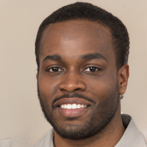 Joyful black young-adult male with short  black hair and brown eyes