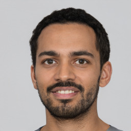 Joyful latino young-adult male with short  black hair and brown eyes