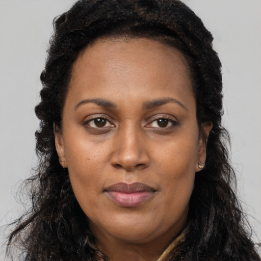 Joyful black young-adult female with long  brown hair and brown eyes