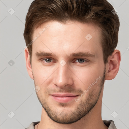 Joyful white young-adult male with short  brown hair and grey eyes