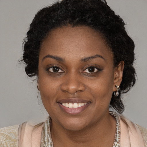 Joyful black young-adult female with long  black hair and brown eyes