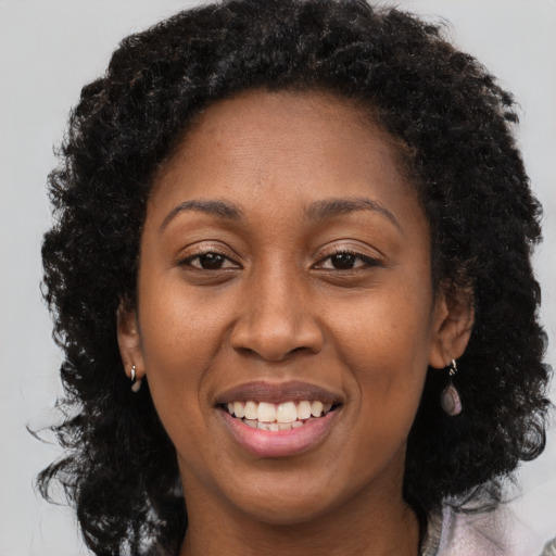 Joyful black adult female with long  brown hair and brown eyes