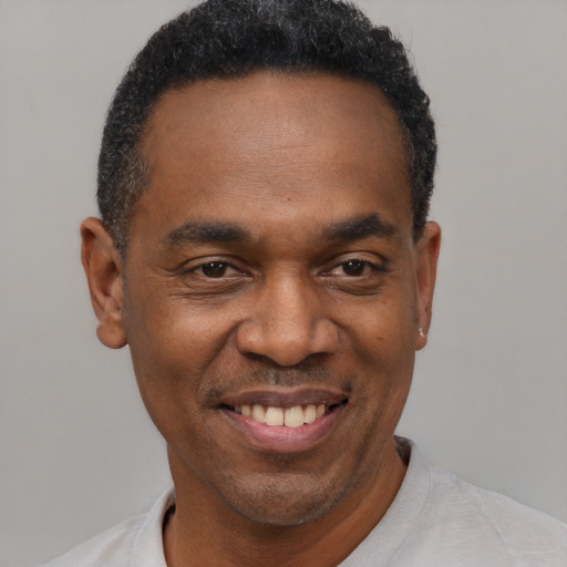 Joyful black adult male with short  black hair and brown eyes