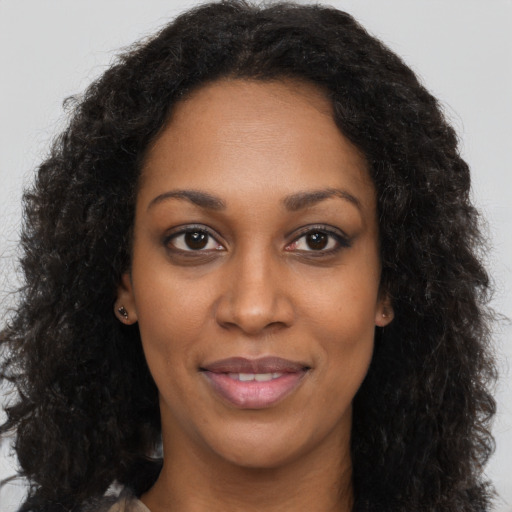 Joyful black young-adult female with long  brown hair and brown eyes