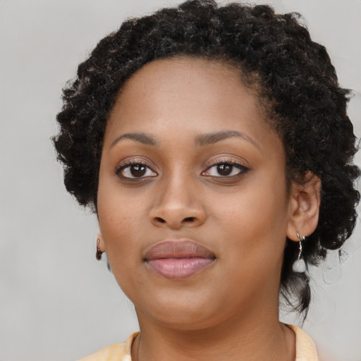 Joyful black young-adult female with long  black hair and brown eyes