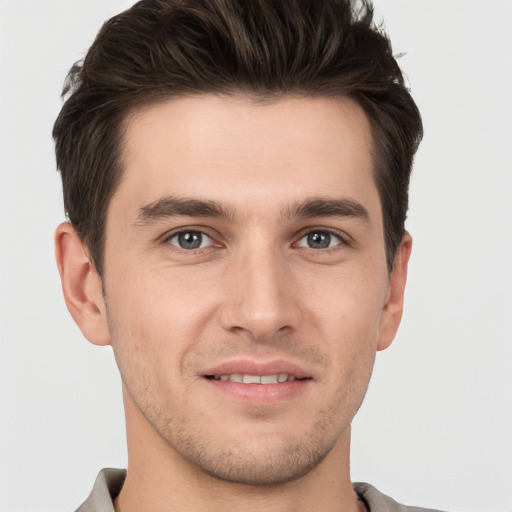 Joyful white young-adult male with short  brown hair and grey eyes