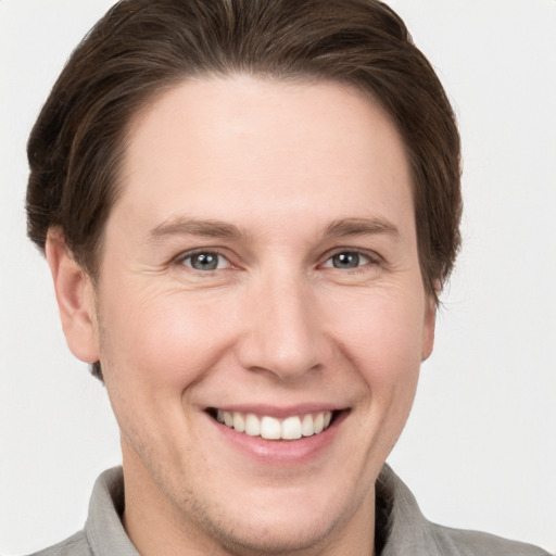 Joyful white young-adult male with short  brown hair and grey eyes