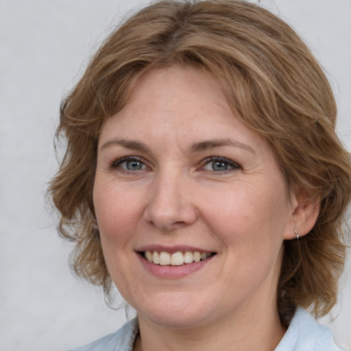 Joyful white adult female with medium  brown hair and blue eyes