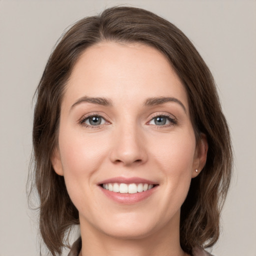 Joyful white young-adult female with medium  brown hair and green eyes