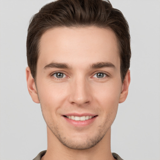 Joyful white young-adult male with short  brown hair and grey eyes