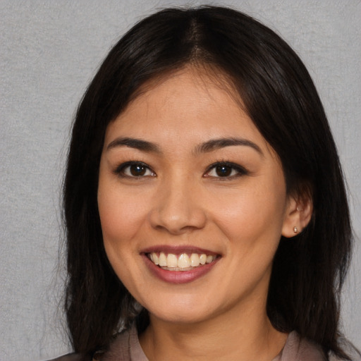 Joyful asian young-adult female with long  brown hair and brown eyes