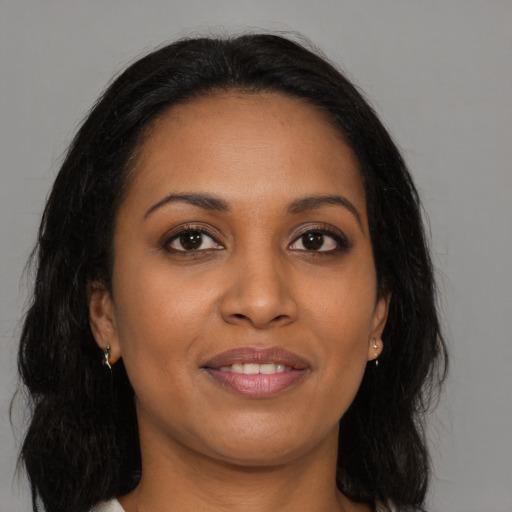 Joyful black young-adult female with long  brown hair and brown eyes