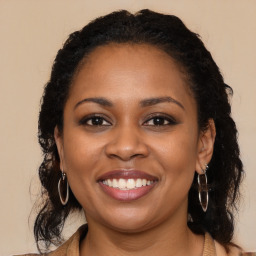 Joyful black young-adult female with long  brown hair and brown eyes