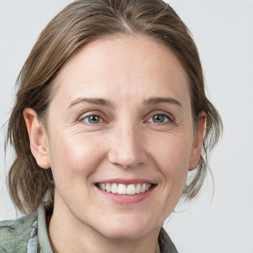 Joyful white young-adult female with medium  brown hair and grey eyes