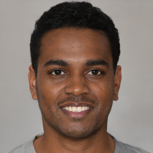 Joyful black young-adult male with short  black hair and brown eyes