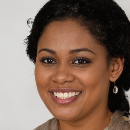 Joyful black young-adult female with long  black hair and brown eyes