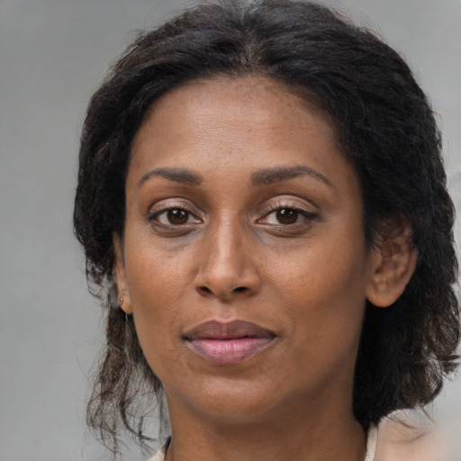 Joyful black adult female with medium  brown hair and brown eyes