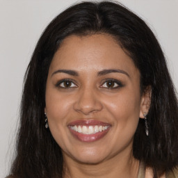 Joyful black young-adult female with long  brown hair and brown eyes