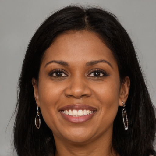 Joyful black young-adult female with long  brown hair and brown eyes