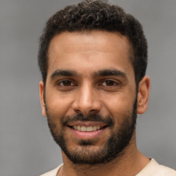 Joyful black young-adult male with short  brown hair and brown eyes