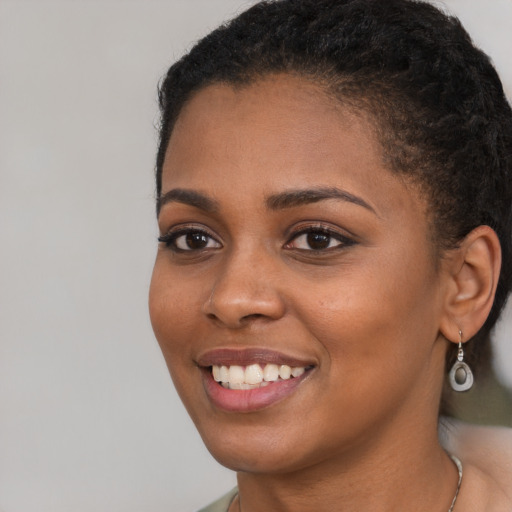 Joyful black young-adult female with short  brown hair and brown eyes