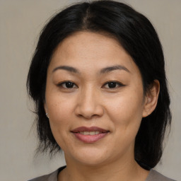 Joyful asian adult female with medium  brown hair and brown eyes