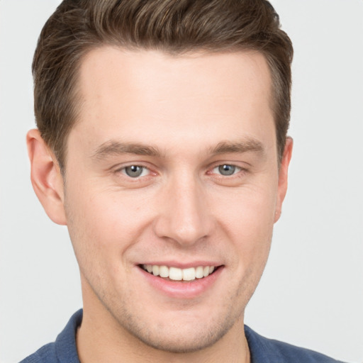 Joyful white young-adult male with short  brown hair and grey eyes